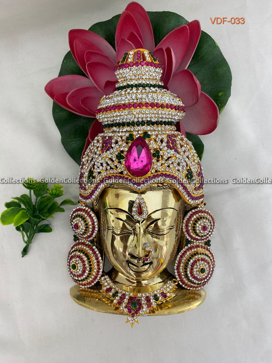 Decorative mask with gold finish, pink gemstone, and green leaves on a white background