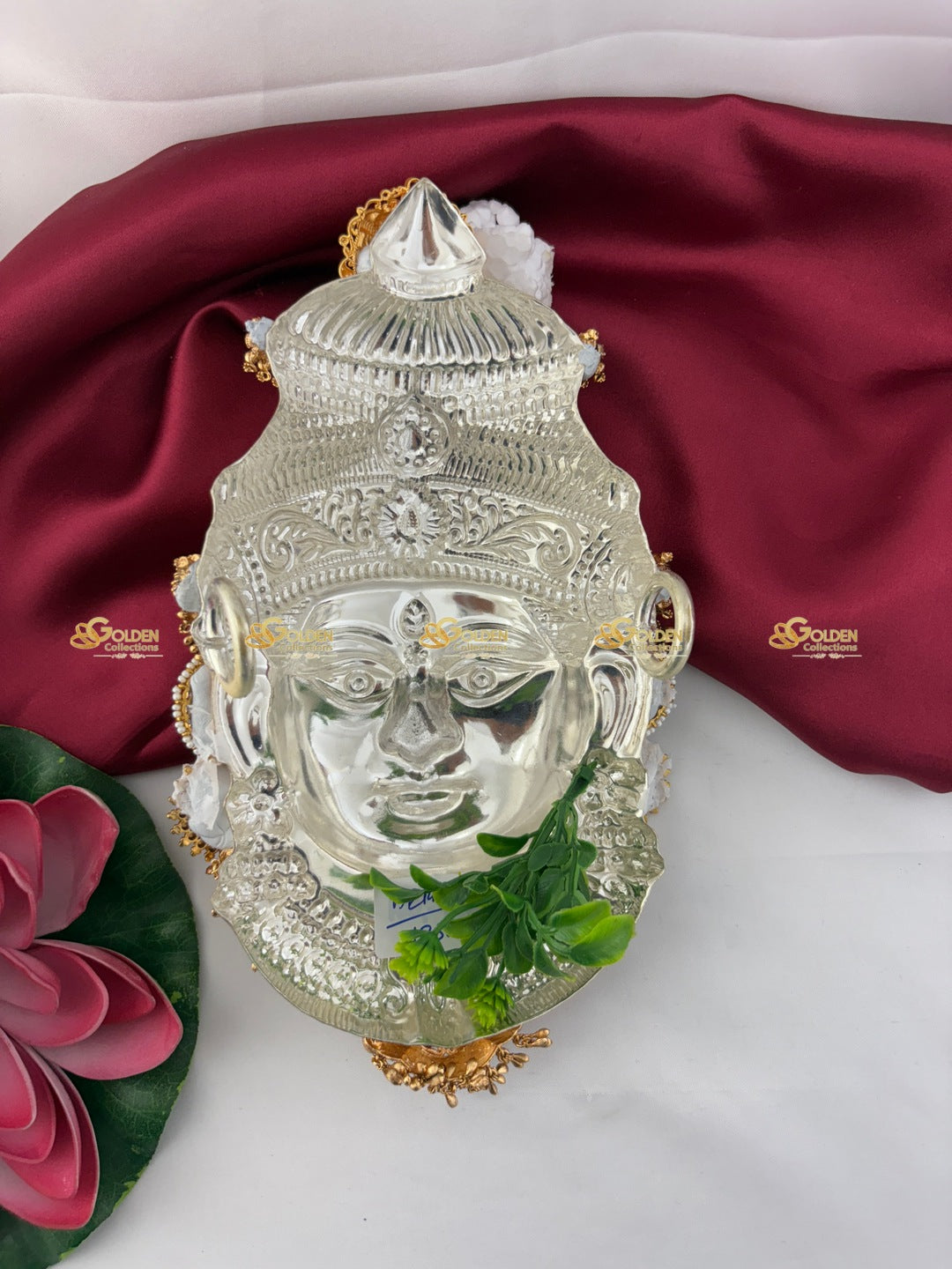 Decorative mask with gold accents on a white surface with a red fabric background
