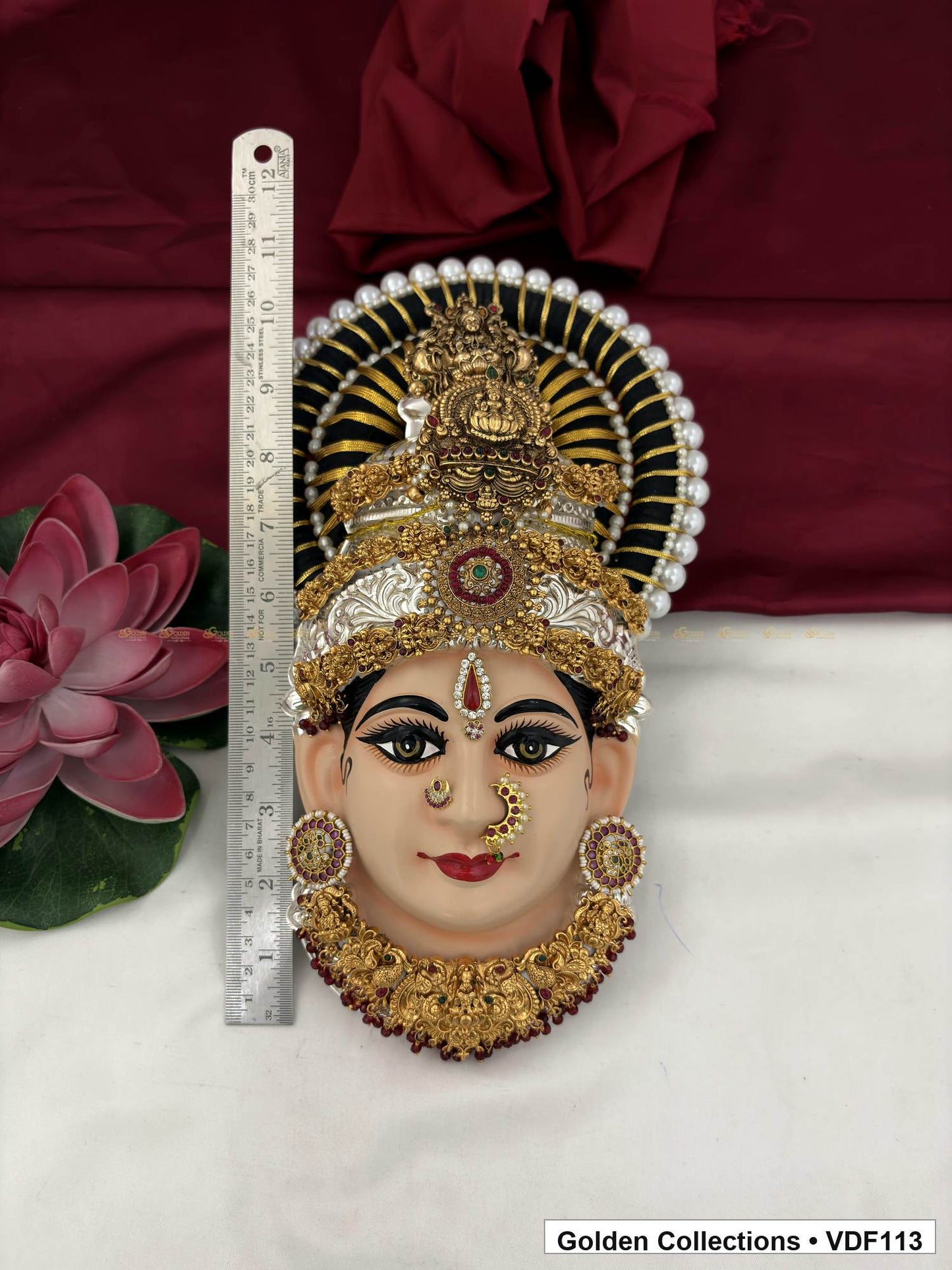 Measurement view of Varalakshmi Tanjore Face with Red-Green Centre Crown and Maroon Fringe Necklace with ruler beside the product