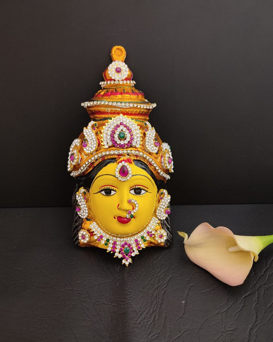 Varalakshmi idol's serene face beautifully embellished with vibrant flowers, enhancing the divine aura and symbolizing prosperity.