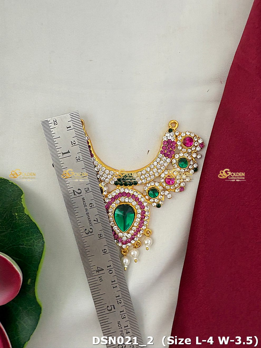 Decorative necklace with gemstones and pearls next to a ruler on a white background