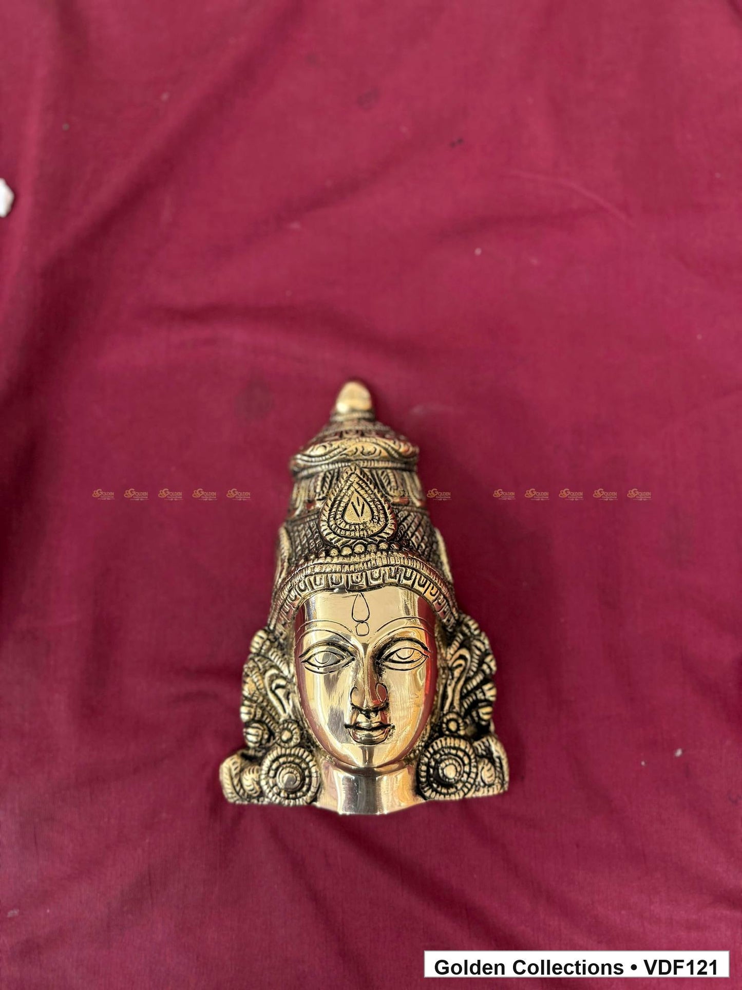 Brass Varalakshmi Face with Tall Embossed Crown and Circular Earrings alternate front view on burgundy fabric
