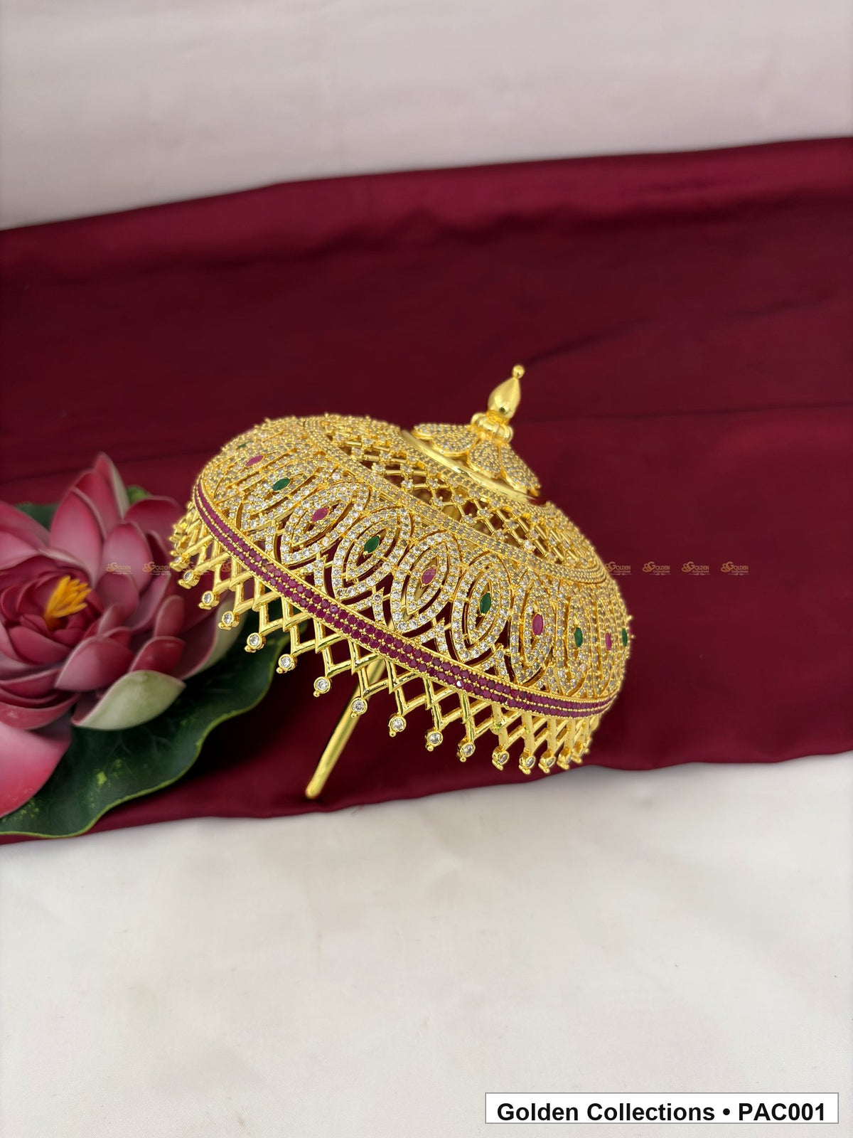 Full-round CZ deity umbrella displayed at an angle, showing its domed form, decorative finial, clear CZ detailing, red and green accents, and lower bead-like drops.