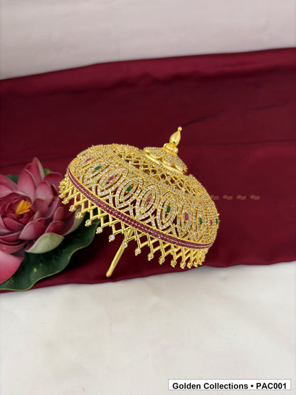 Full-round CZ deity umbrella displayed at an angle, showing its domed form, decorative finial, clear CZ detailing, red and green accents, and lower bead-like drops.