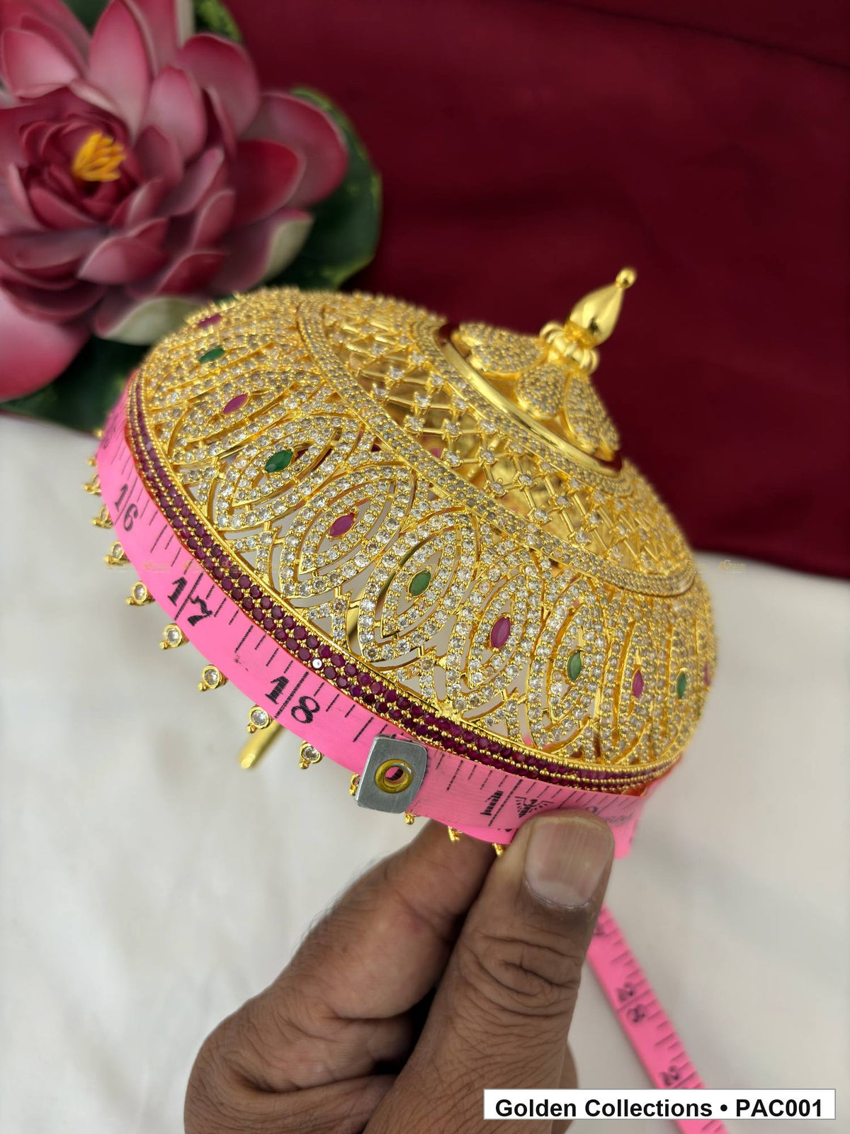Close measurement view of the CZ deity umbrella beside a pink measuring tape, showing the decorated dome, finial, lower edge, and bead-like drops.