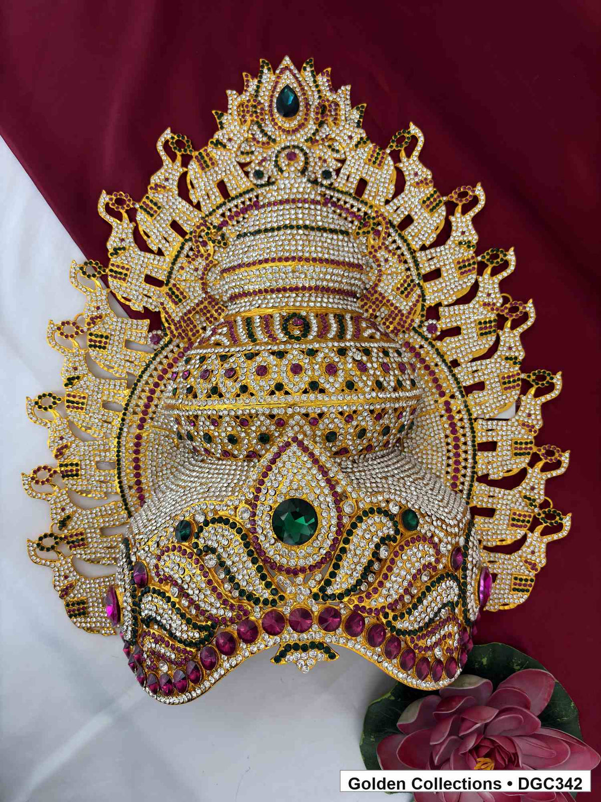Front view of the deity crown with elephant motifs, tiered stone decoration and green and magenta accents.