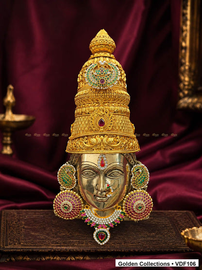 Fully Decorated Brass Varalakshmi Face with Nakshi Crown and Green Jadau Earrings displayed against a burgundy devotional backdrop