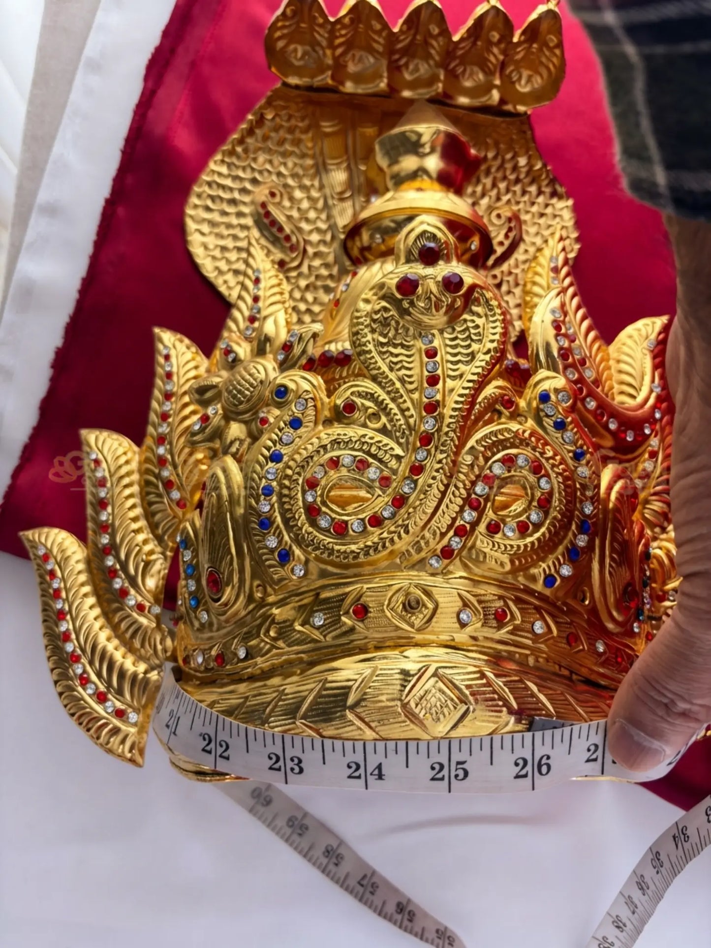 Golden Collections Gold Plated Nagaraja Naga Kireedam Crown - Close-up view showing the circumference being measured, highlighting the detailed gold plating and vibrant stones.