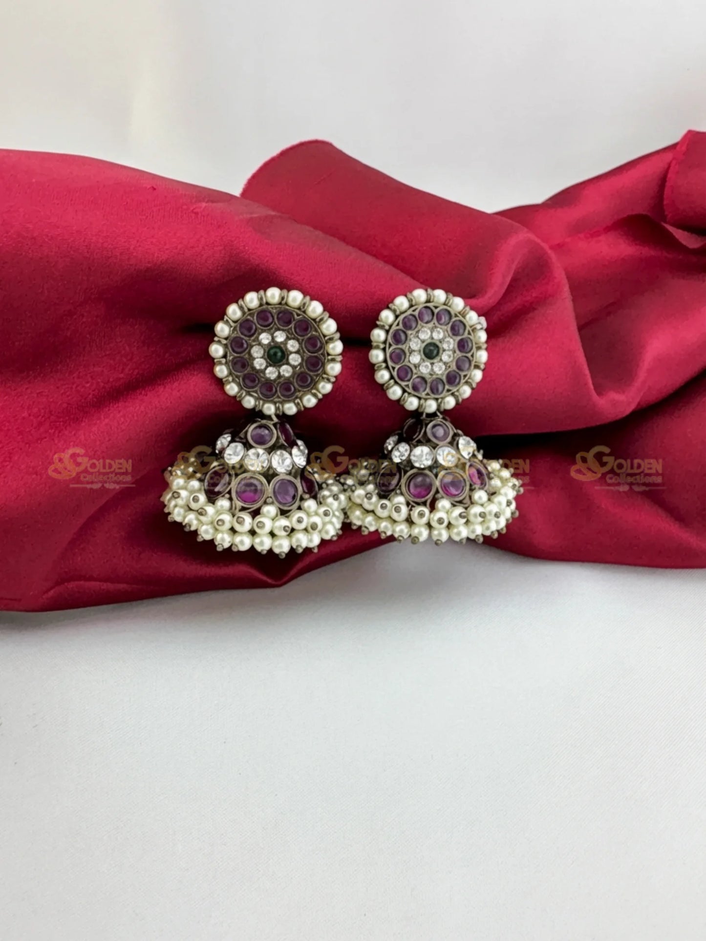 Golden Collections Kemp Black Bharatanatyam Jhumka Earrings - Main view showcasing the studs, domes, and pearl fringe held by hand.