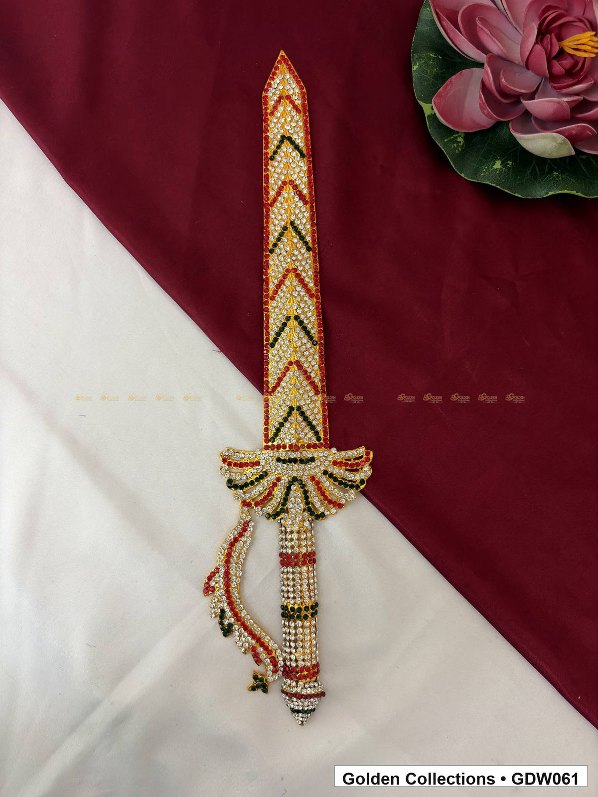Full front view of the stone-studded deity sword with red and green pointed blade motifs, a fan-shaped guard and curved side guard.