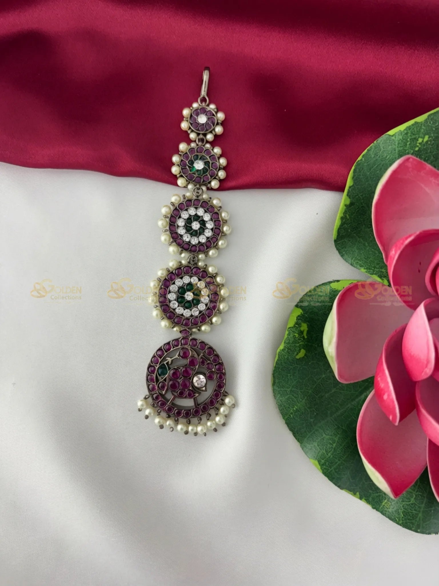 Golden Collections Black Kemp Maang Tikka - Front view showcasing four circular motifs with maroon and green stones, outlined by white stones and pearls.